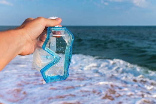 A hand holds snorkeling goggles against the background of the sea or ocean and sky. Diving goggles and snorkeling equipment in hands near the beach