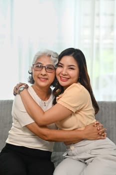 Portrait of happy senior mother and adult daughter hugging and enjoying tender moment at home.