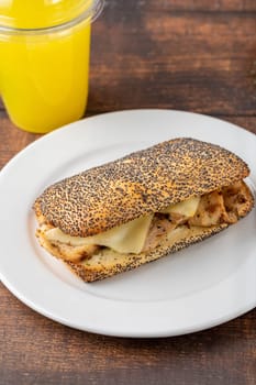 Cheddar cheese and chicken sandwich on white porcelain plate on wooden table