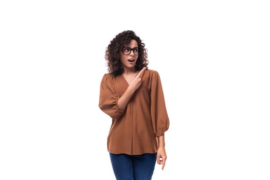 young surprised european curly woman with curled hair on a curling iron is dressed in a brown shirt.