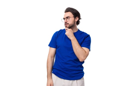 young brutal stylish brunette man with a beard dressed in a blue t-shirt with a mockup on a white background.