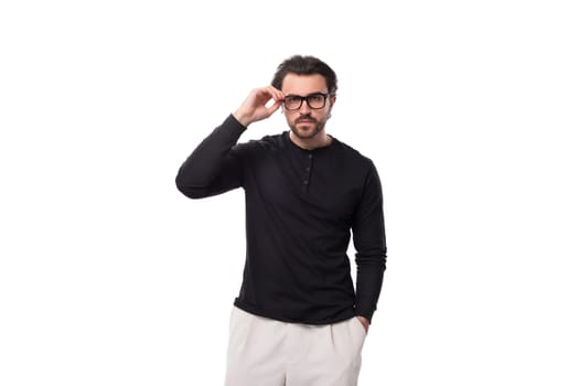 well-groomed young caucasian man with black hair and beard put on glasses for vision correction.