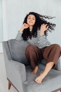 Beautiful oriental brunette woman sitting on grey armchair