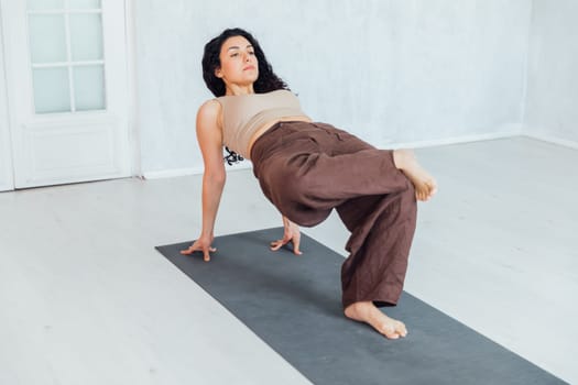 Fit woman making cobra pose on yoga mat, exercising in studio over panoramic window