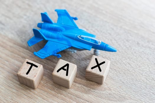 TAX word on wooden cubes, toy military jet. High quality photo