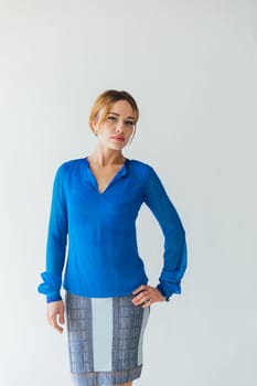 woman in blue clothes stands against a white wall