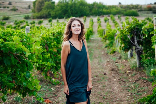 woman in a blue dress stands in vineyards