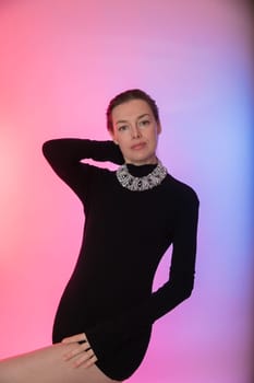 woman in a black dress poses on a pink background