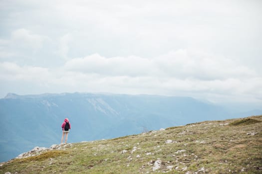 woman on a hike stands on a mountain and looks at the mountains nature hiking journey