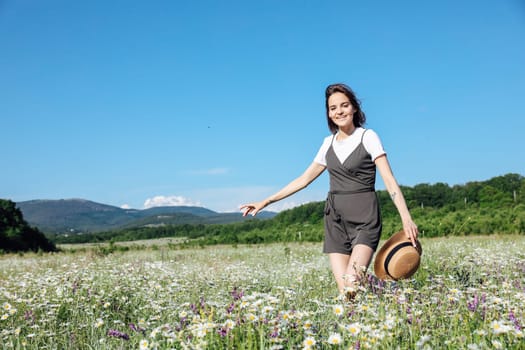 in nature a woman in a straw hat plays in a field with daisies flowers