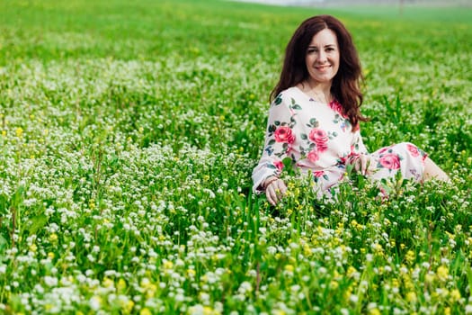 beautiful woman sitting in a green clearing in nature