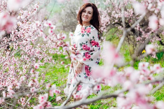 woman stands in a garden of flowering pink trees nature park spring