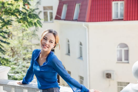 woman in blue clothes stands at the white railing on the street