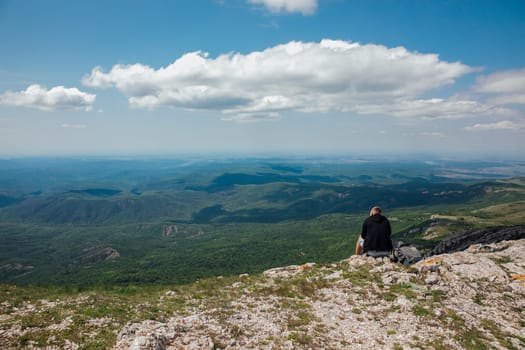 a man sits on a mountain and looks into the distance at the mountains view of his father's journey hike