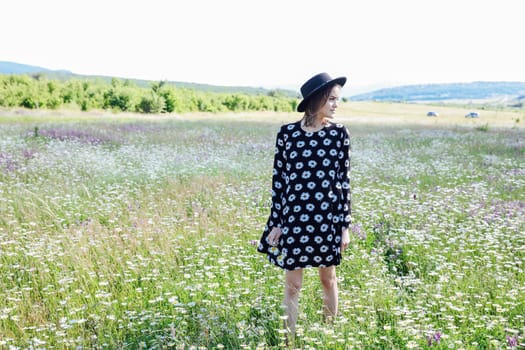 woman in a polka dot dress and a hat in nature on a walk in the field