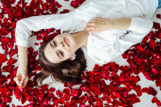 woman lies on the floor in red rose petals