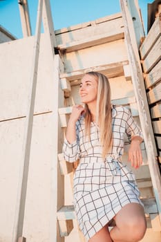 a beautiful blonde sitting on the wooden stairs of the house