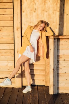 blonde girl in a yellow jacket sitting on a wooden building