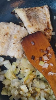 fried fish fillet with onions in a frying pan, food dinner lunch. High quality photo