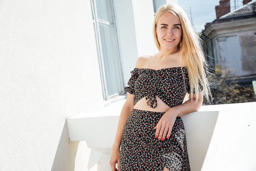 a blonde beautiful woman in summer clothes on the balcony in the room