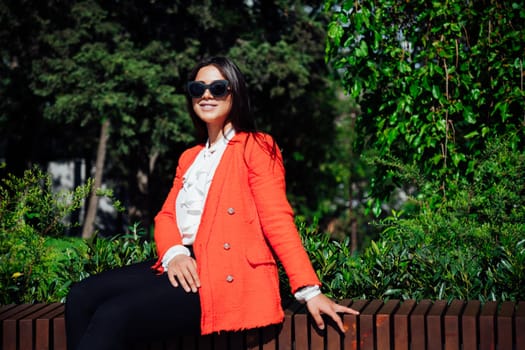 a woman brunette sitting on a bench outside walk rest