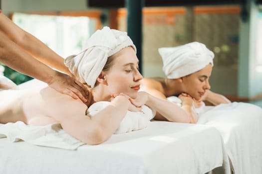 Couple of beautiful young woman lie on white spa bed during having back massage. Attractive caucasian woman having back massage at traditional spa room. Relaxing and healthy concept Tranquility.