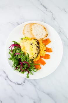 a mix of salmon, arugula salad, white bread and baked avocado with cheese