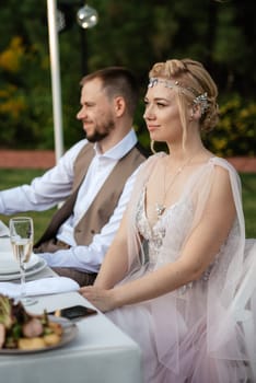 evening wedding family dinner in the forest with light bulbs and candles