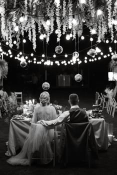 evening wedding family dinner in the forest with light bulbs and candles