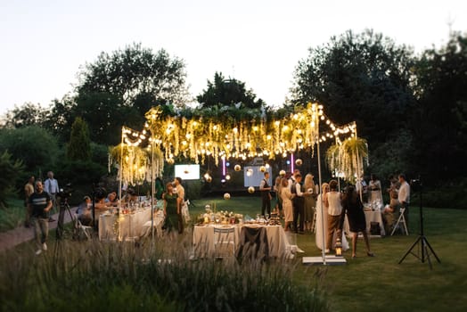 evening wedding family dinner in the forest with light bulbs and candles