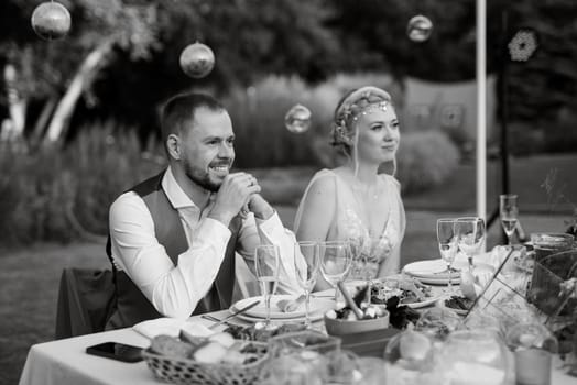 evening wedding family dinner in the forest with light bulbs and candles