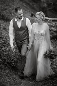 wedding walk of the bride and groom in a coniferous park in summer in elven accessories