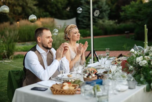 evening wedding family dinner in the forest with light bulbs and candles