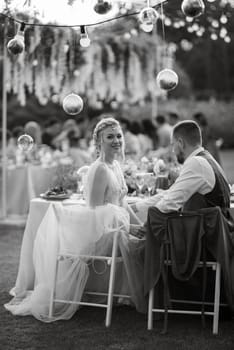 evening wedding family dinner in the forest with light bulbs and candles