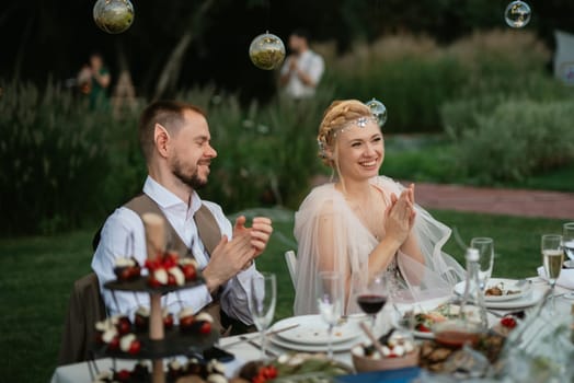 evening wedding family dinner in the forest with light bulbs and candles