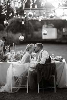 evening wedding family dinner in the forest with light bulbs and candles