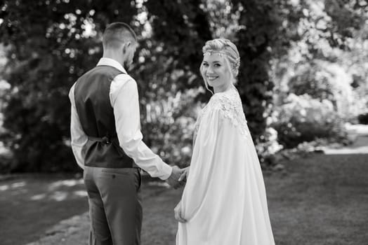 wedding walk of the bride and groom in a coniferous park in summer in elven accessories