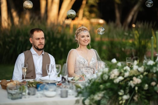 evening wedding family dinner in the forest with light bulbs and candles