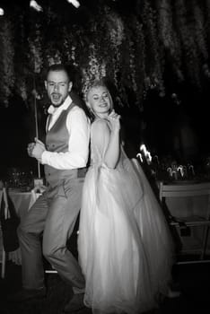 the first wedding dance of the bride and groom in the glade of the country club in the light of sunset and warm garlands