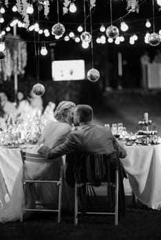 evening wedding family dinner in the forest with light bulbs and candles