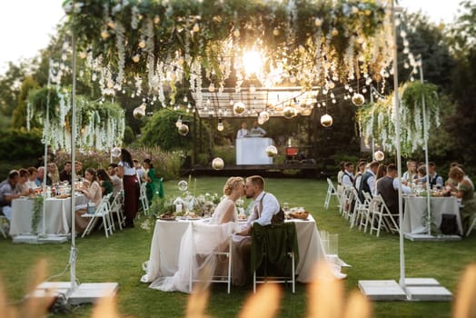 evening wedding family dinner in the forest with light bulbs and candles