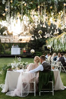 evening wedding family dinner in the forest with light bulbs and candles