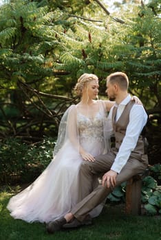 wedding walk of the bride and groom in a coniferous park in summer in elven accessories