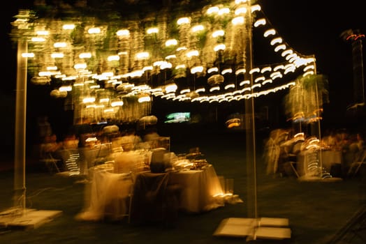 evening wedding family dinner in the forest with light bulbs and candles