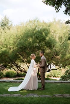 the first meeting of the bride and groom in wedding outfits in the park