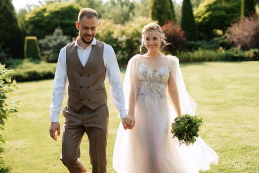 wedding walk of the bride and groom in a coniferous park in summer in elven accessories