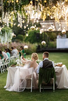 evening wedding family dinner in the forest with light bulbs and candles