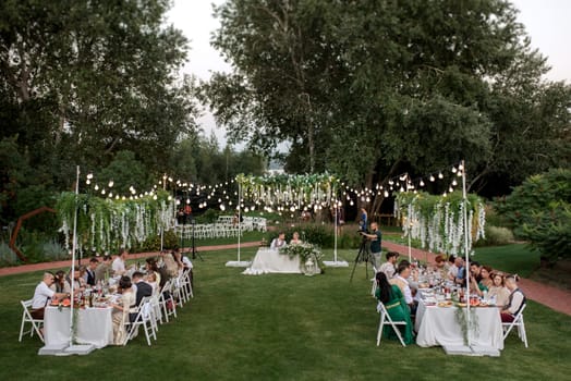 evening wedding family dinner in the forest with light bulbs and candles