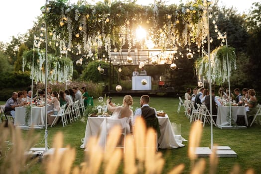 evening wedding family dinner in the forest with light bulbs and candles