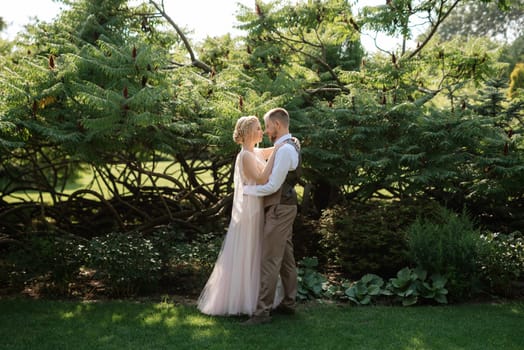 wedding walk of the bride and groom in a coniferous park in summer in elven accessories